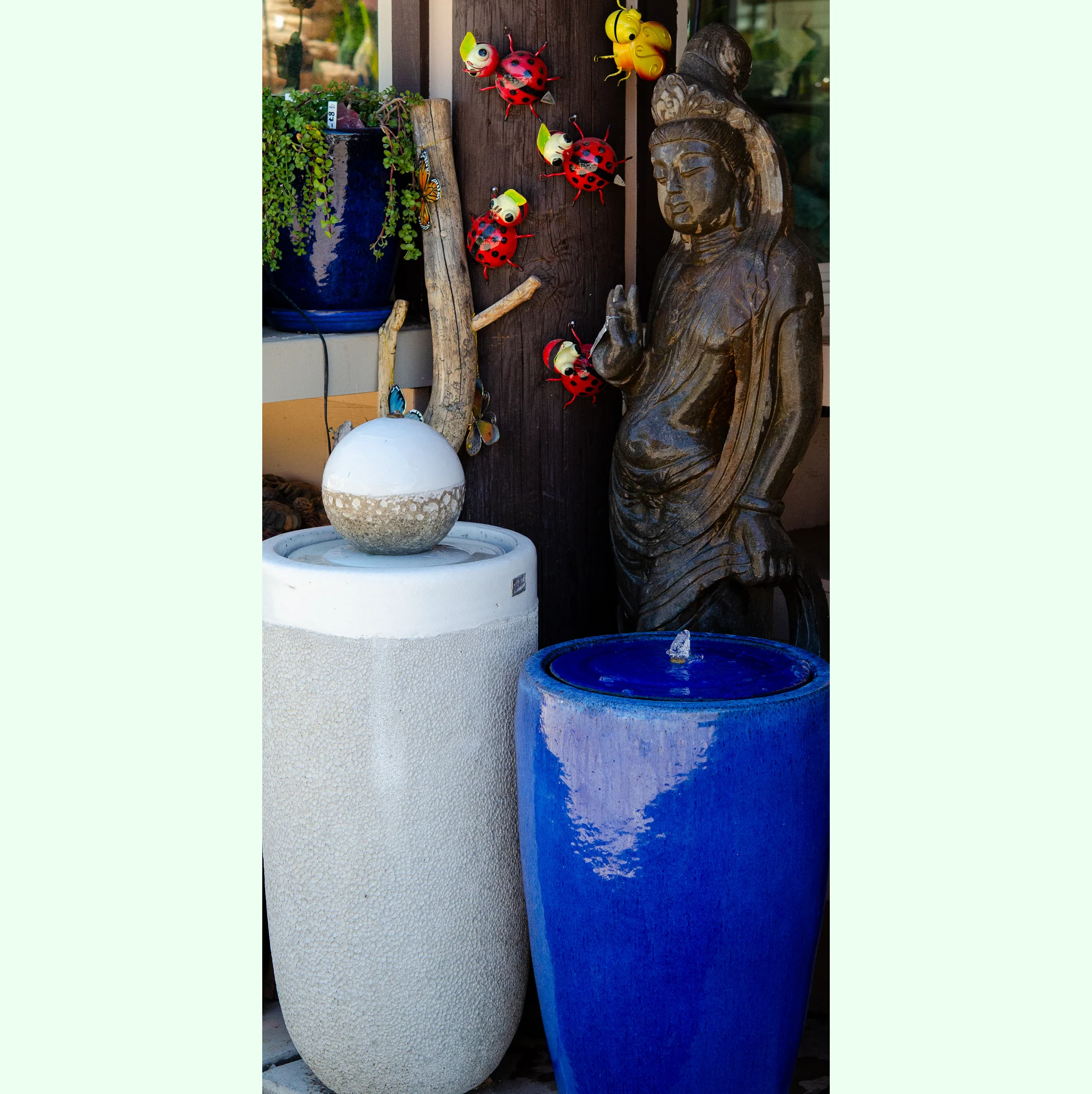 Statue of a Buddha sitting next to a blue vase with a water fountain in front of it