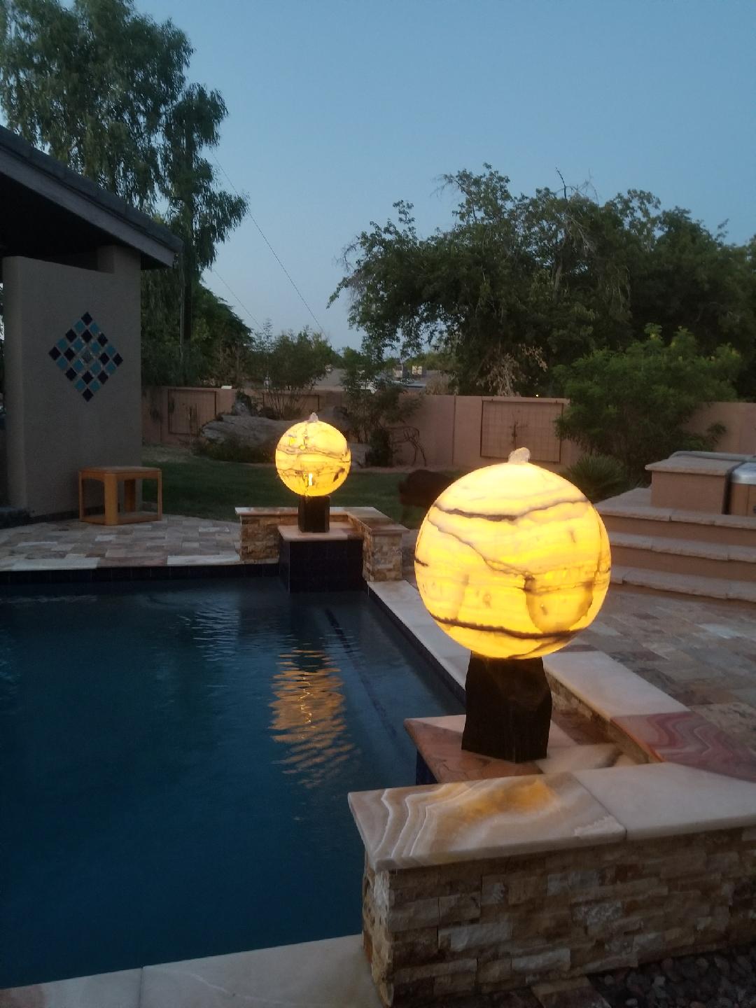 glowing stone fountains installed on the edge of a pool
