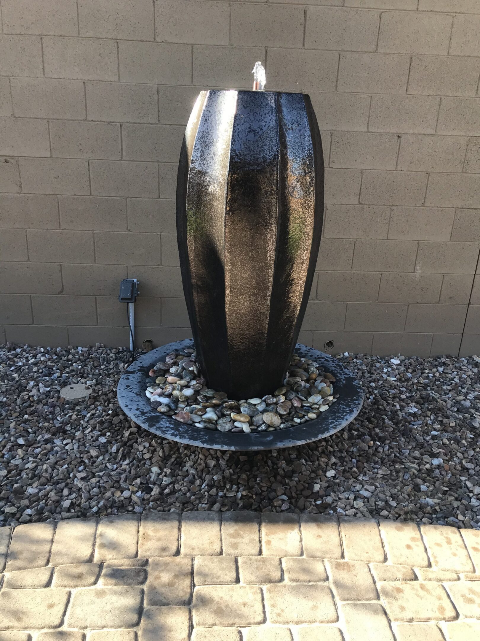 metallic pot installed in a basin with water coming out over the top and flowing into the basin below