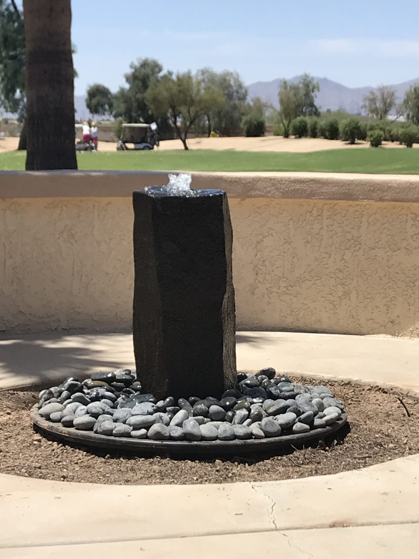 short basalt column fountain installed in a backyard that overlooks a golf course